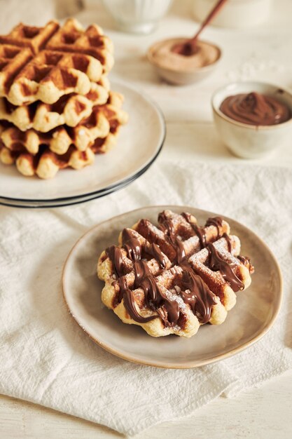 Tir vertical de délicieuses gaufres avec trempette au chocolat sur un tableau blanc