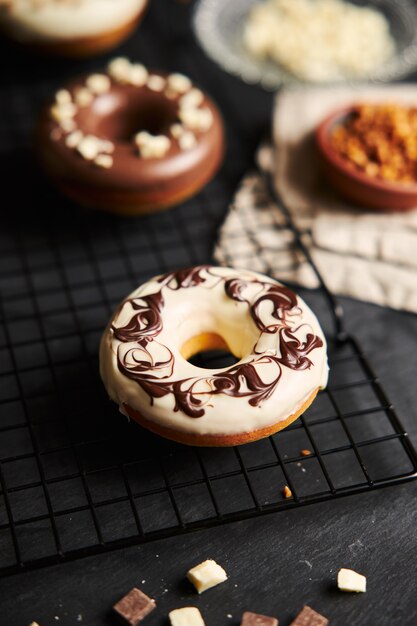 Tir vertical d'un délicieux beignet recouvert de glaçage au chocolat blanc et brun sur une table