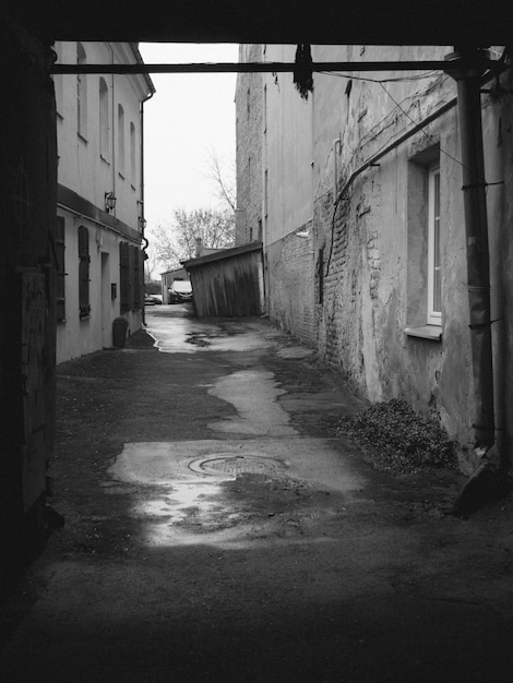 Tir vertical à l'échelle de gris d'une rue avec de vieux bâtiments et de l'eau de pluie dans le sol