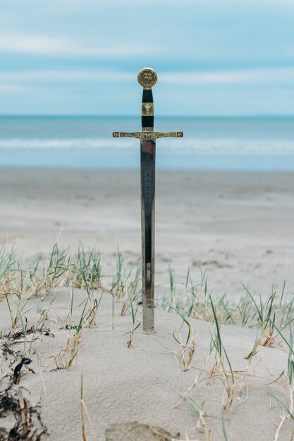 Tir vertical d'une épée dans la plage de sable