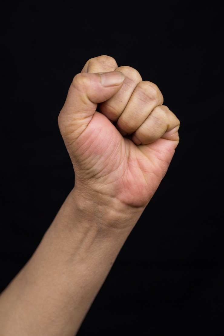 Photo gratuit tir vertical d'une femme asiatique tenant son poing en signe de concept d'autonomisation force-femmes