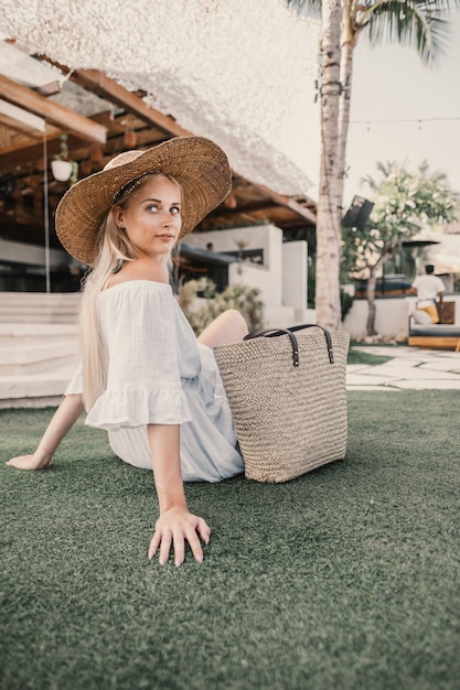 Tir vertical d'une femme assise sur l'herbe à côté d'un bâtiment