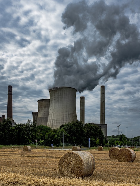 Tir vertical de la fumée montante rendant l'air pollué et des hayricks sur le terrain