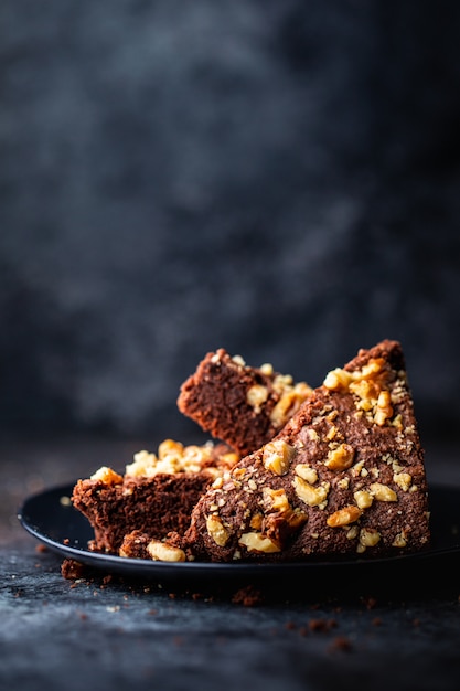 Tir vertical d'un gâteau au chocolat aux noix dans une assiette noire avec un flou