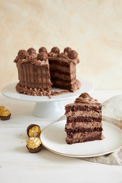 Tir vertical d'un gâteau au chocolat et une tranche sur une assiette à côté de quelques morceaux de chocolat