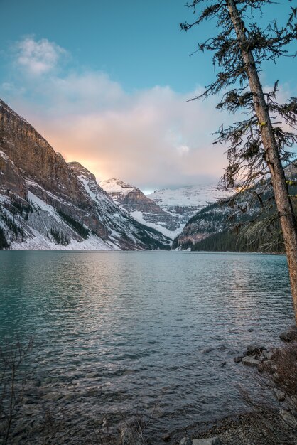 Tir vertical d'un lac au centre des montagnes enneigées et le ciel lumineux en arrière-plan