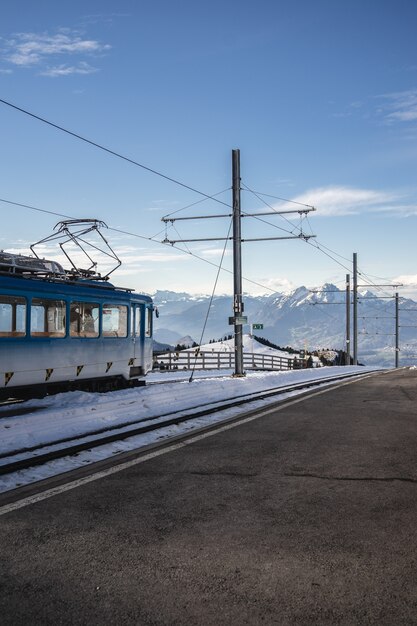 Tir vertical d'une ligne aérienne à côté de la voie ferrée d'un train électrique sous un ciel bleu clair