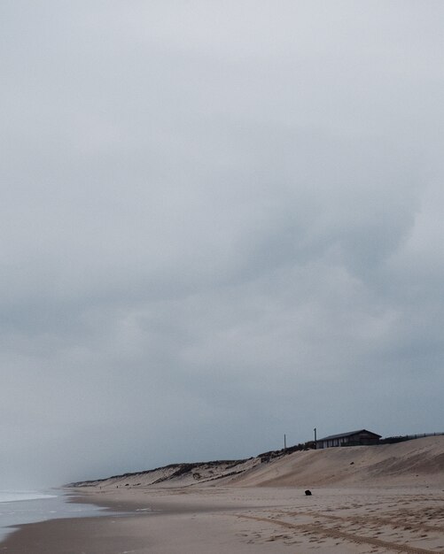 Tir vertical d'une maison solitaire au bord de la plage sous le ciel nuageux