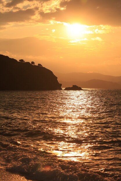 Tir vertical de la mer entourée de montagnes au coucher du soleil