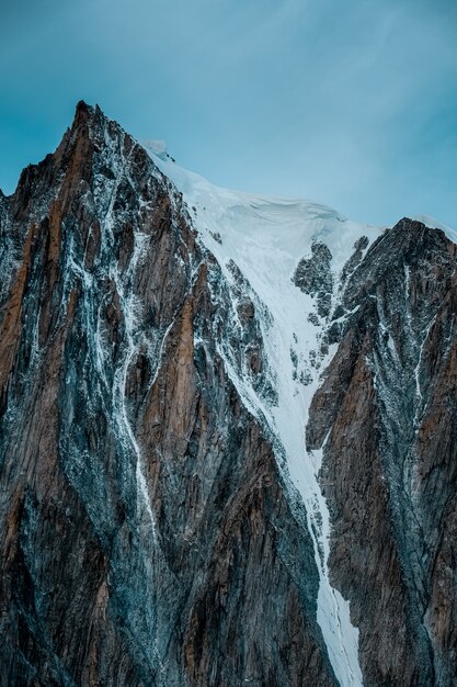 Tir vertical d'une montagne enneigée avec un ciel clair en arrière-plan