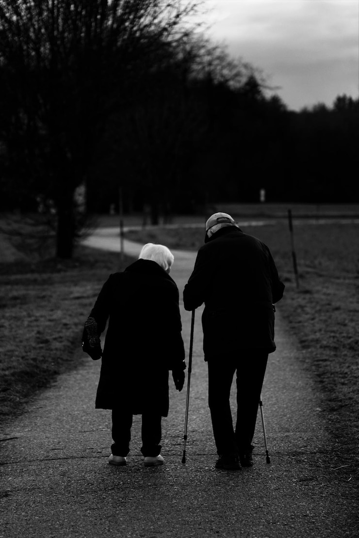 Photo gratuit tir vertical en niveaux de gris de vieux conjoints marchant dans le parc - concept de vieillissement