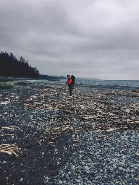 Tir vertical d'une personne debout sur une plage rocheuse à côté de l'océan
