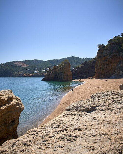 Tir vertical des rochers sur la rive de la mer à la plage publique de Playa Illa Roja en Espagne