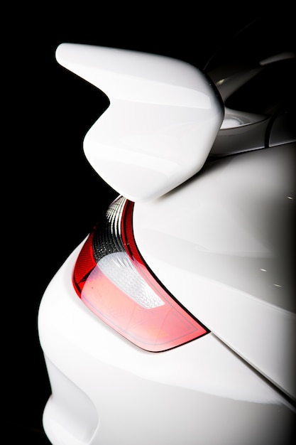 Tir vertical d'un spoiler sur une voiture de luxe blanche sous les lumières isolées