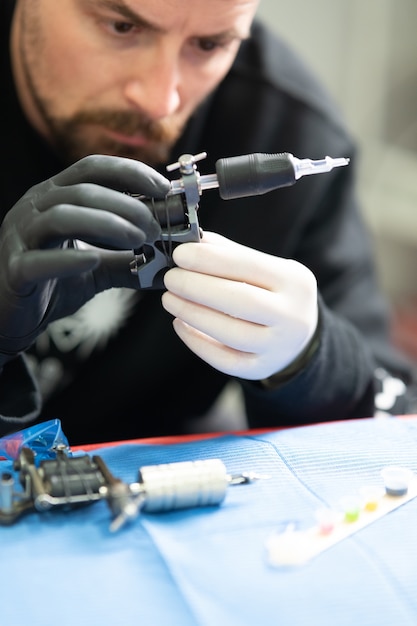 Tir vertical d'un tatoueur professionnel assemblant une machine à tatouer