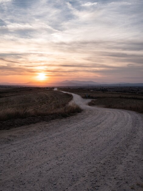 Tir vertical d'une voie dans un champ herbeux avec la vue imprenable sur le coucher du soleil dans le