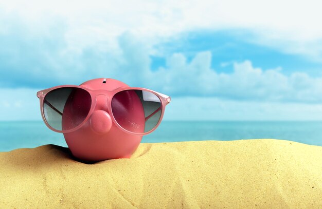 Tirelire d'été avec des lunettes de soleil sur la plage