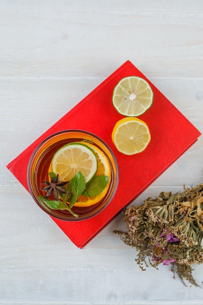 Photo gratuite tisane et agrumes sur un napperon rouge avec un bouquet de fleurs