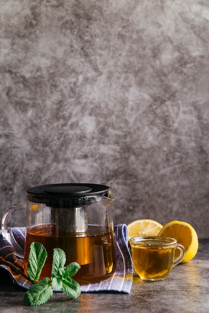Tisane au citron et à la menthe dans une tasse en verre transparent et une théière