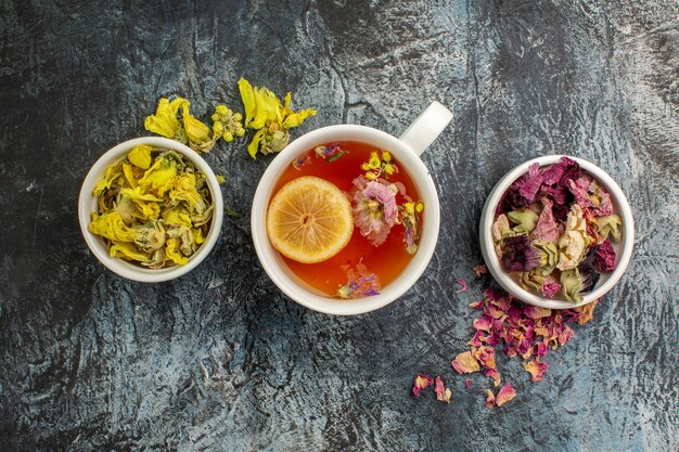 Tisane avec bols de fleurs séchées sur fond gris