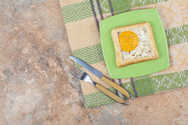 Toast aux oeufs aux épices sur plaque verte avec couverts et nappe