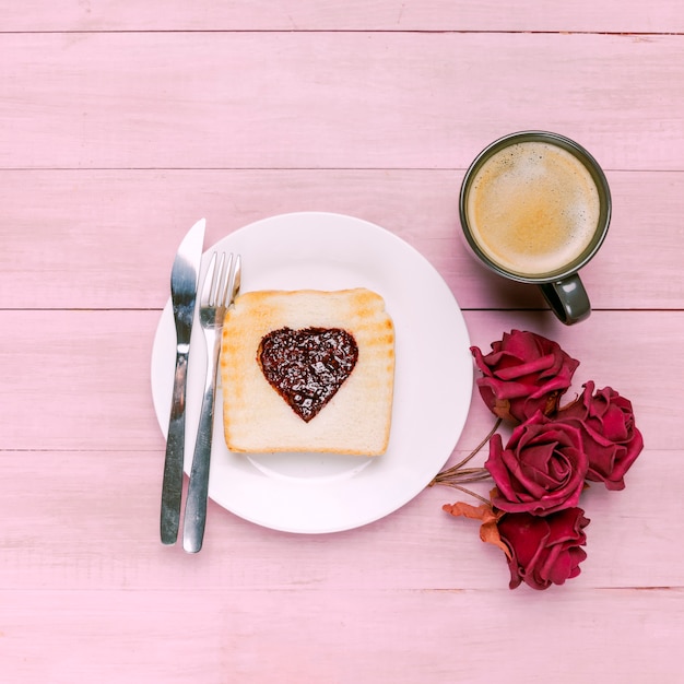 Toast avec de la confiture en forme de coeur avec des roses et du café