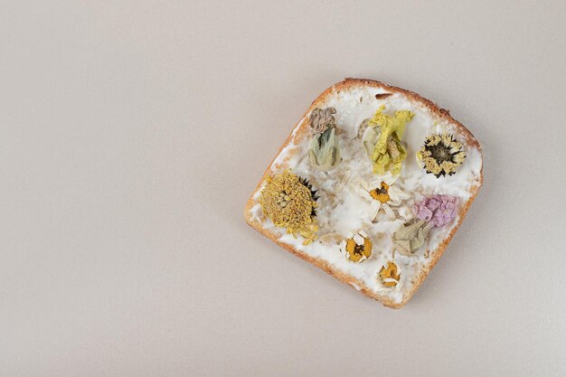 Toast avec fleurs séchées et farine sur table grise.