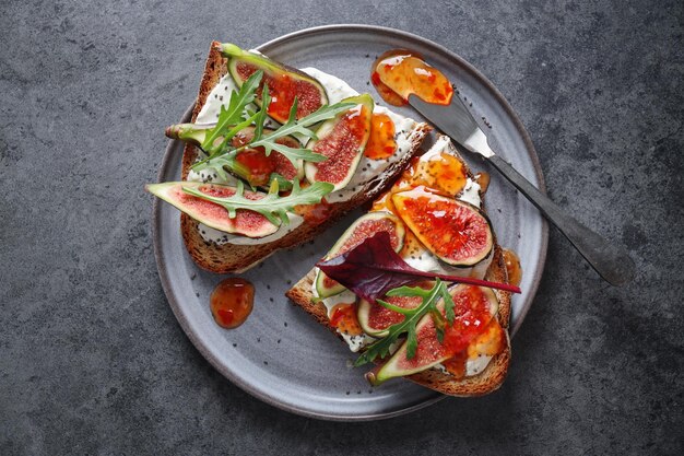 Toast sandwich aux figues sur fromage à la crème avec confiture servi sur assiette