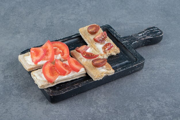 Toasts croustillants aux tomates sur planche de bois.