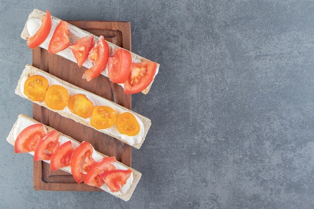 Toasts croustillants aux tomates sur planche de bois.