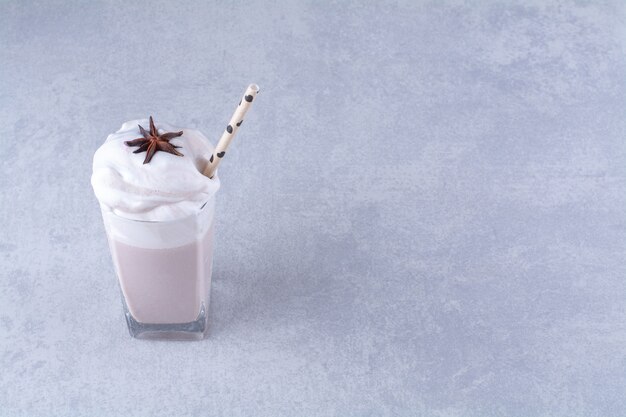 Étoile d'anis sur un verre de délicieux milk-shake avec de la paille sur une table en marbre.