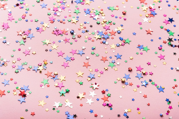 Étoiles de confettis colorés sur fond rose