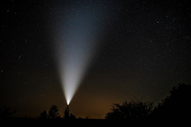 Étoiles filantes vues près d'une lampe de poche tenue par l'homme