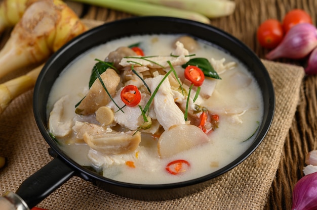 Tom Kha Kai dans une poêle à frire avec des feuilles de lime kaffir, de la citronnelle, de l'oignon rouge, du galanga et du piment.