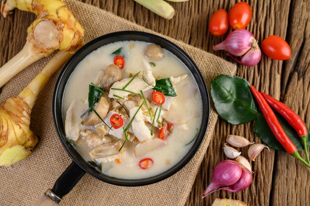 Tom Kha Kai dans une poêle à frire avec des feuilles de lime kaffir, de la citronnelle, de l'oignon rouge, du galanga et du piment.