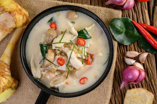 Tom Kha Kai dans une poêle à frire avec des feuilles de lime kaffir, de la citronnelle, de l'oignon rouge, du galanga et du piment.