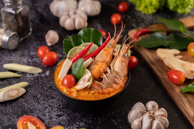 Tom Yum Kung dans un bol avec tomate, chili, citronnelle, ail, citron et feuilles de lime kaffir