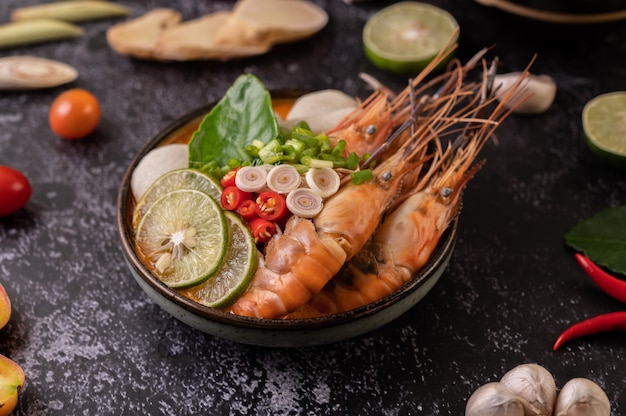 Tom Yum Kung dans un bol avec tomate, chili, citronnelle, ail, citron et feuilles de lime kaffir