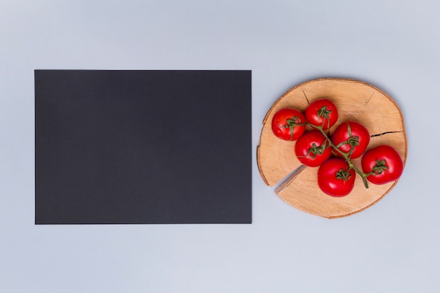 Tomate fraîche rouge sur une souche d&#39;arbre près de l&#39;état noir sur fond gris