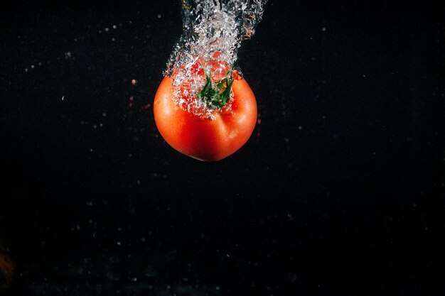 La tomate fraiche tombe dans l&#39;eau et fait des bulles