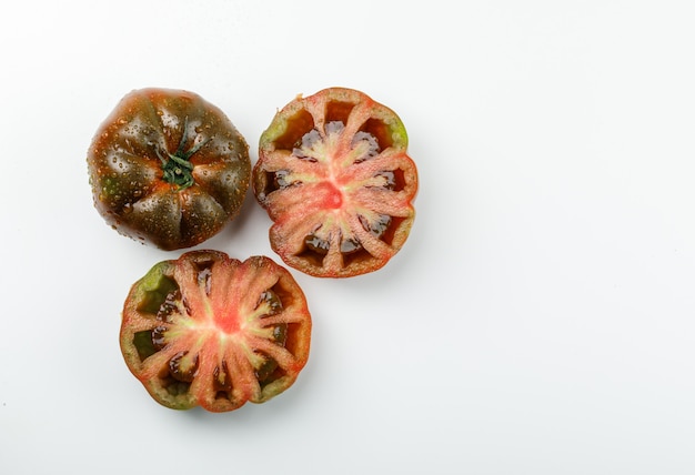 Tomate kumato en tranches sur un mur blanc. mise à plat.