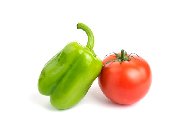 Tomate et poivre biologiques frais isolés sur une surface blanche.