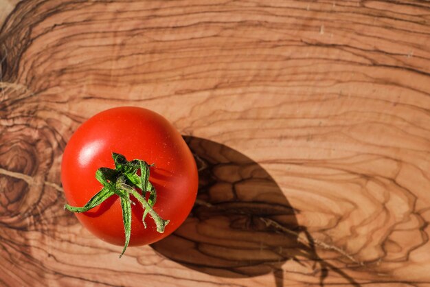 Tomate rouge mûre d'une ferme biologique sur une planche à découper en bois vue de dessus en plein soleil avec espace de copie préparant un plat