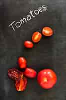 Photo gratuite tomates biologiques séchées et fraîches sur tableau noir par dessus tableau noir