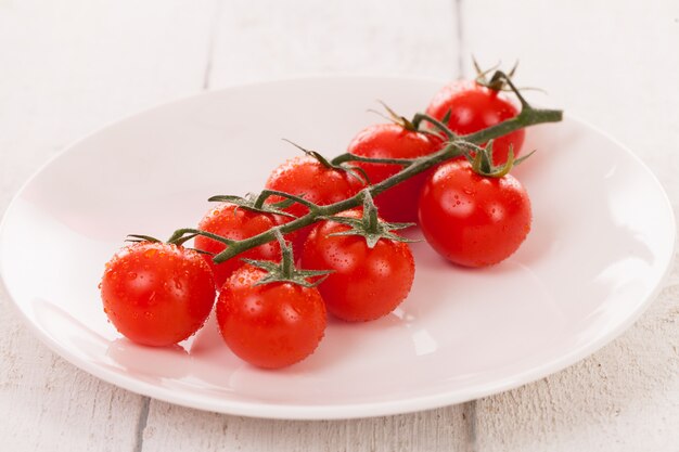 Tomates cerises sur une branche dans une assiette