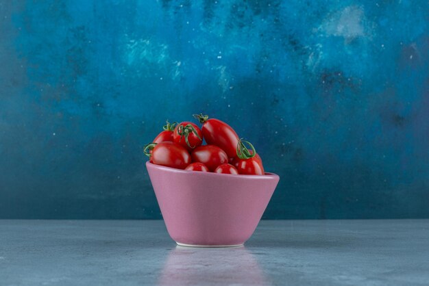 Tomates cerises dans une tasse sur bleu.