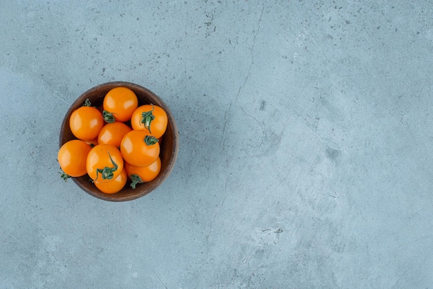 Tomates cerises jaunes dans une tasse en bois.