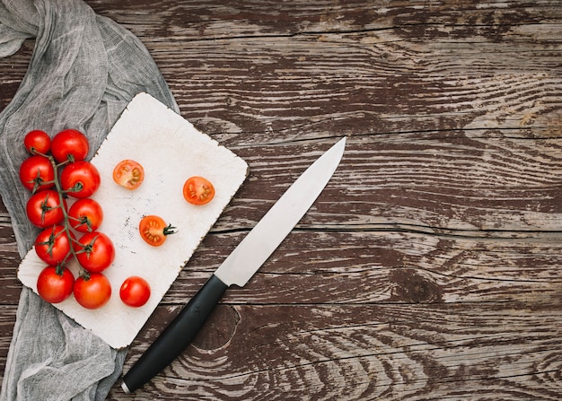 Tomates cerises rouges sur une planche à découper avec un couteau sur le bureau en bois