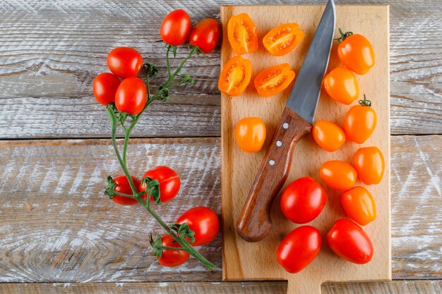 Tomates avec couteau sur planche de bois et à découper, pose à plat.