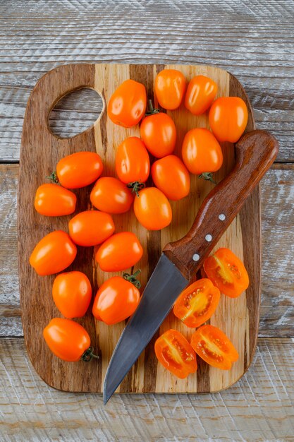Tomates avec couteau plat posé sur planche de bois et à découper